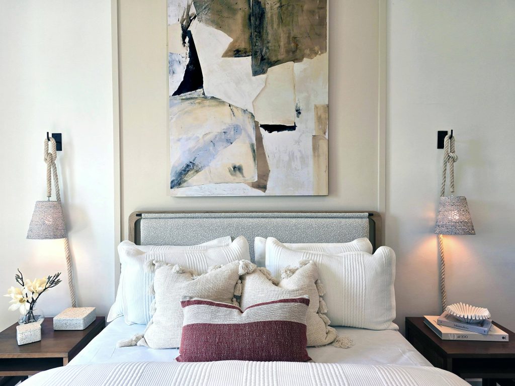 lit avec un tableau abstrait au dessus et coussins nombreux sur le lit
