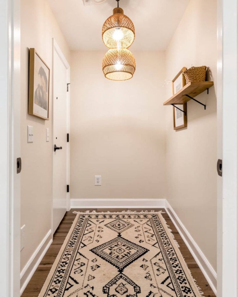 une entrée couloir mur beige et tapis blanc et noir au sol