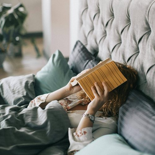 personne dans son lit avec un livre sur la tête